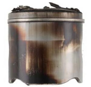 The piston crown and skirt contain deposits. Excessive deposits reduce efficiency and can lead to engine failure.