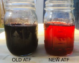 Used transmission fluid that is dark brown and new transmission fluid that is reddish and opaque.