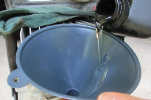 Adding air compressor oil to compressor. 